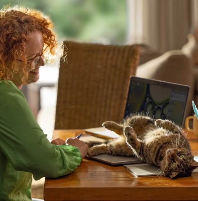 A kitten playfully lays on a woman's laptop | NEXGARD® Parasite Protection