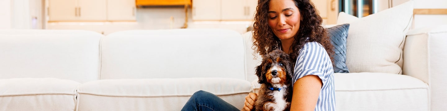 Woman cuddling small dog indoors