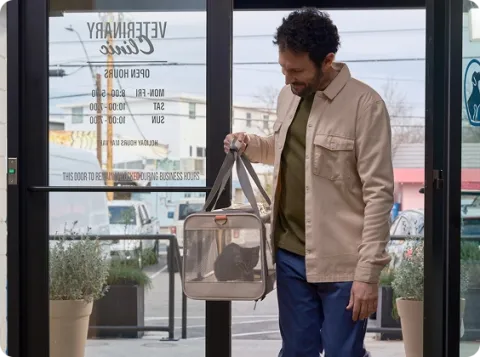 man holding a kitten inside a carrier 